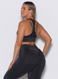 Left side profile view of a model wearing our Shimmer Seamless Bra in black sparkle color along with the matching leggings