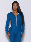 Front profile view of a model facing forward wearing our signature jacket in azure color along with a matching leggings 