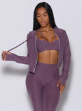 front profile view of a model facing forward wearing our signature jacket in regal purple color along with a matching leggings and bra 