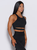 Right side profile view of a model wearing our black sliced tank bra along with a matching black bombshell leggings