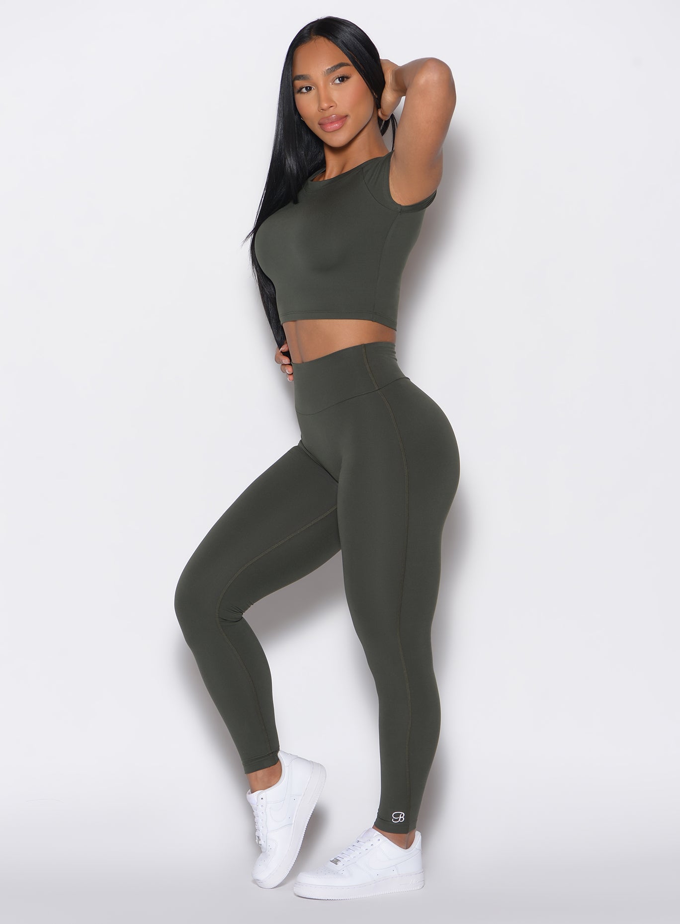  left side view of a model facing to her left wearing our Smooth Leggings and the matching Tee in Deep Ivy color