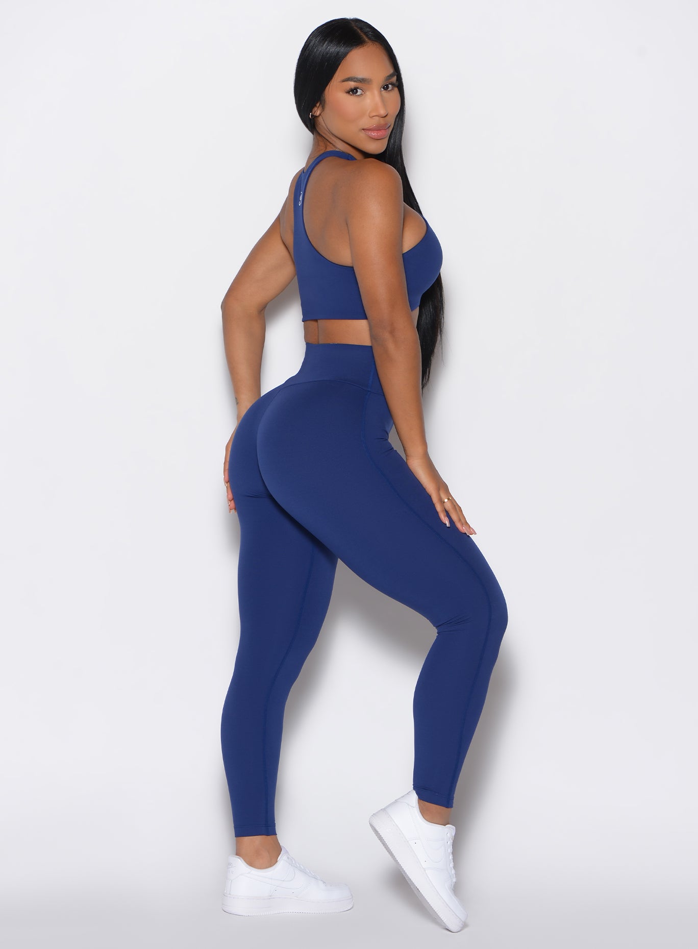 Right side profile view of a model facing to her right wearing our Smooth Leggings and the matching bra in Royal Indigo color