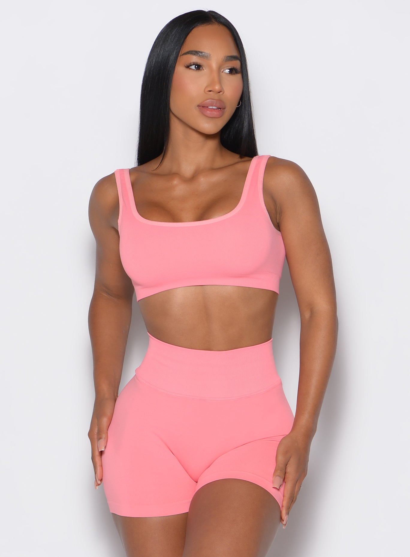 Front profile view of a model wearing our square neck bra in flamingo color along with the matching shorts 
