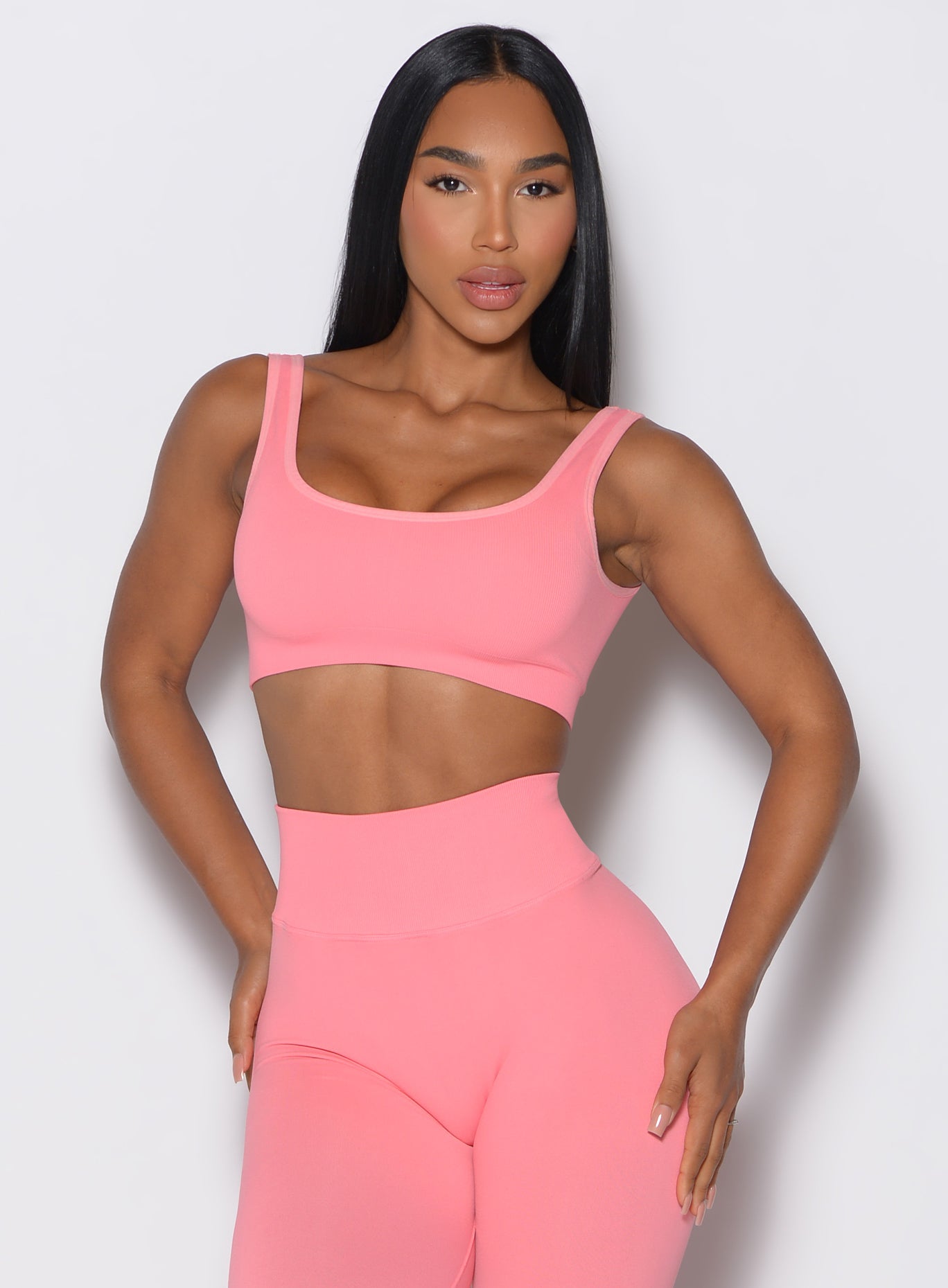 front profile view of a model wearing our square neck bra in flamingo color complemented by a matching shorts