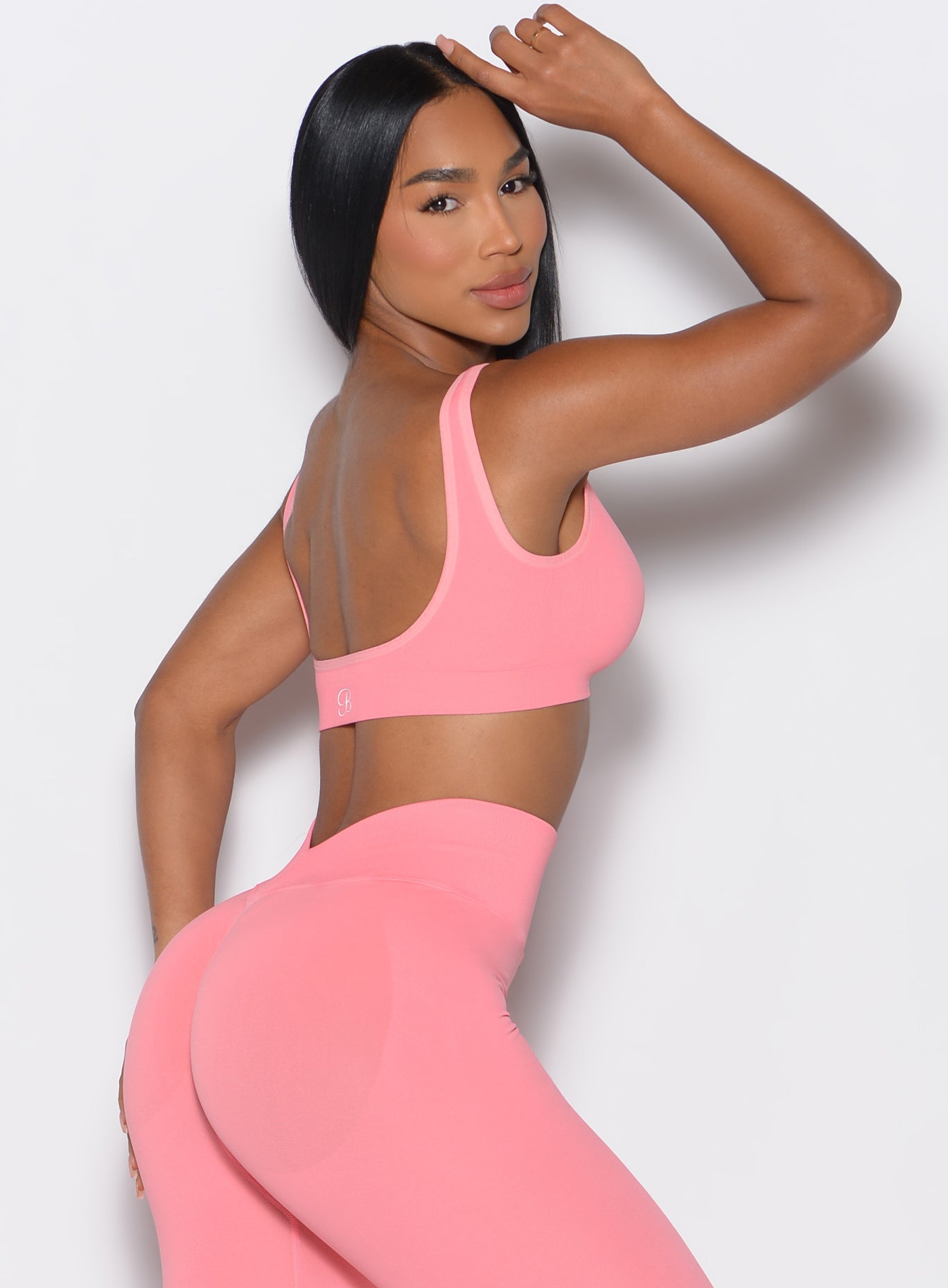 right side profile view of a model facing the camera wearing our square neck bra in flamingo color complemented by a matching shorts