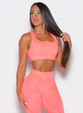 Front profile view of a model facing to the right wearing our Square Neck Bra in coral reef color along with the matching leggings