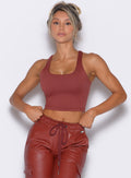 front profile view of our model holding the waistband of the matching liquid cargos wearing the Sugar Tank Bra in brick red color