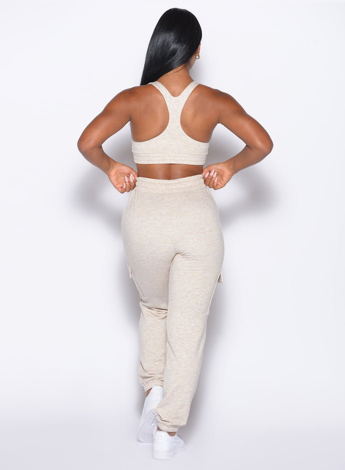 back profile view of our model adjusting the waistband wearing the Sweat Joggers in Heathered Oatmeal color