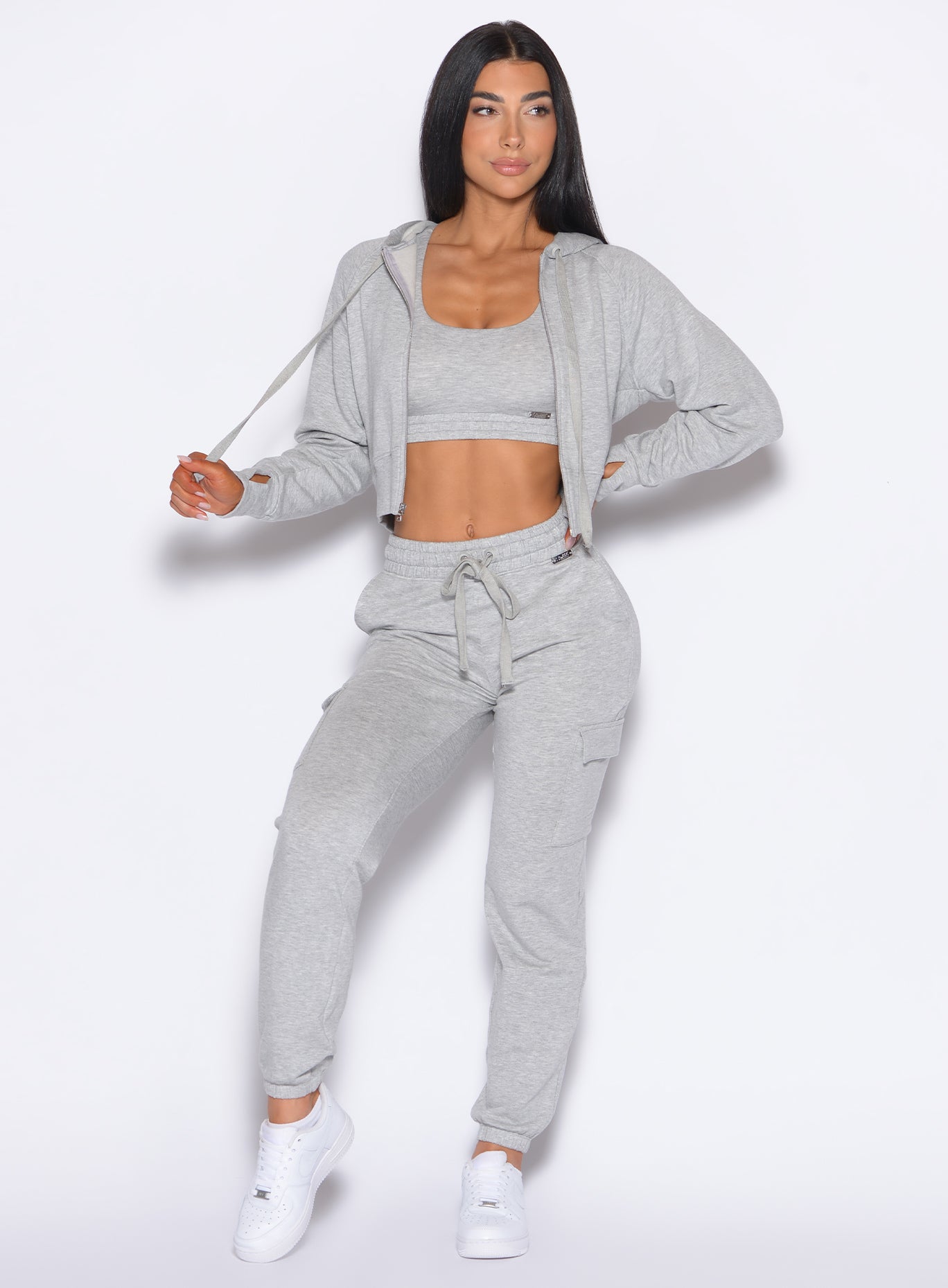 front profile view of our model looking to the left and pulling the hoodie string wearing the Sweat Joggers in Light Heather grey color