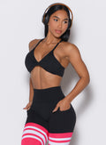 Front profile view of a model facing to her left wearing our black Twist Mini Bra complimented by a matching thigh high