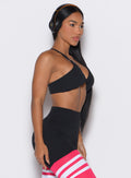 right side profile view of a model facing forward wearing our black Twist Mini Bra complimented by a matching thigh high