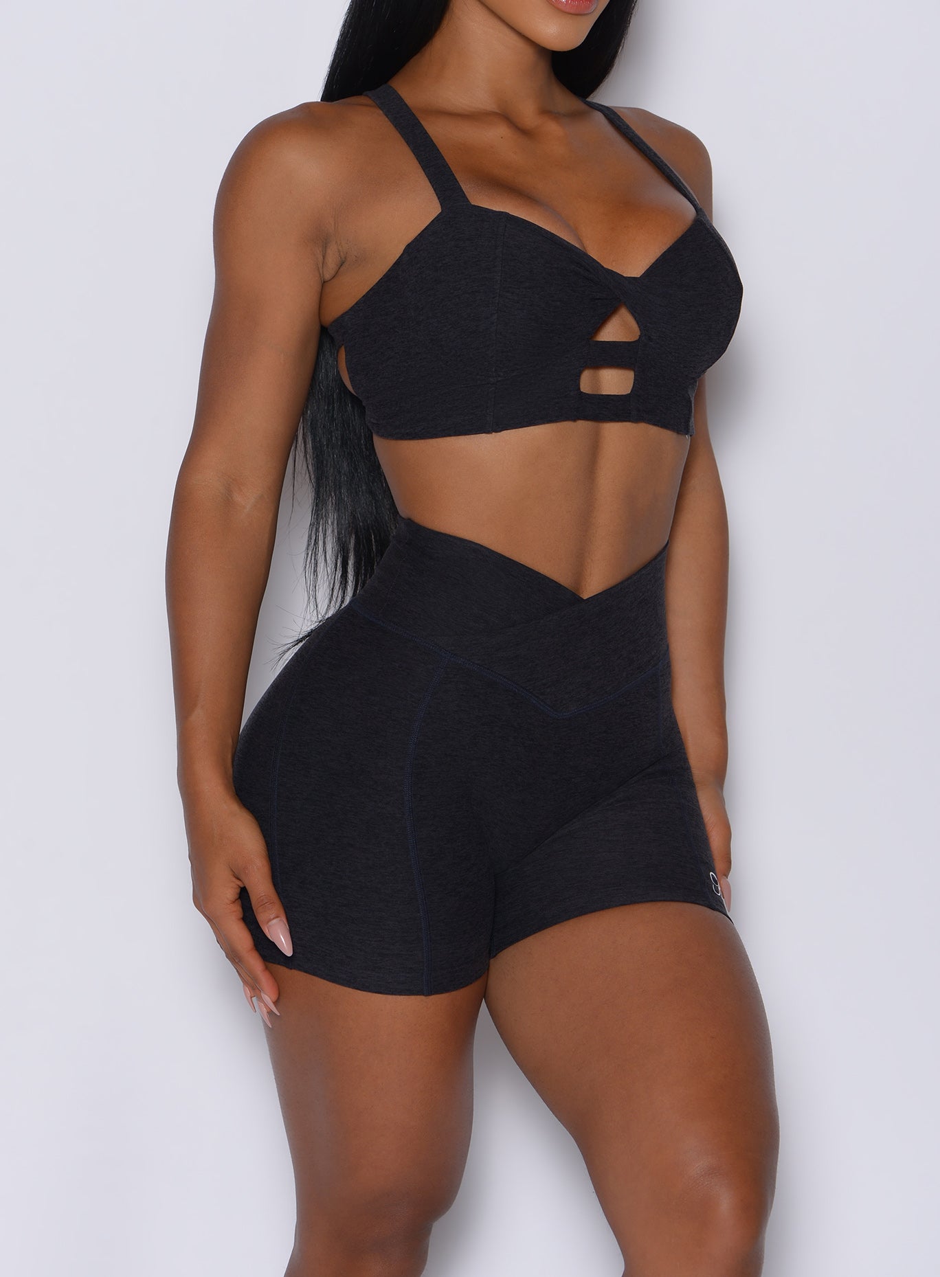 right side profile view of a model wearing our black Tiny Waist Shorts along with the matching bra