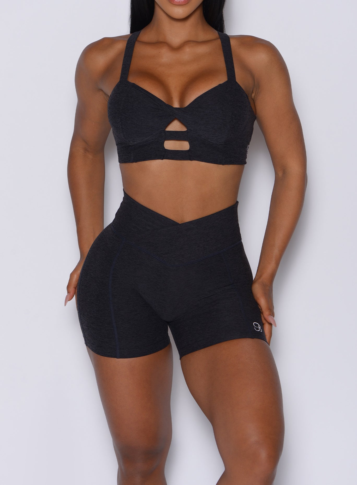 zoomed in front view of a model wearing our Tiny Waist Shorts in Onyx color and a matching sports bra