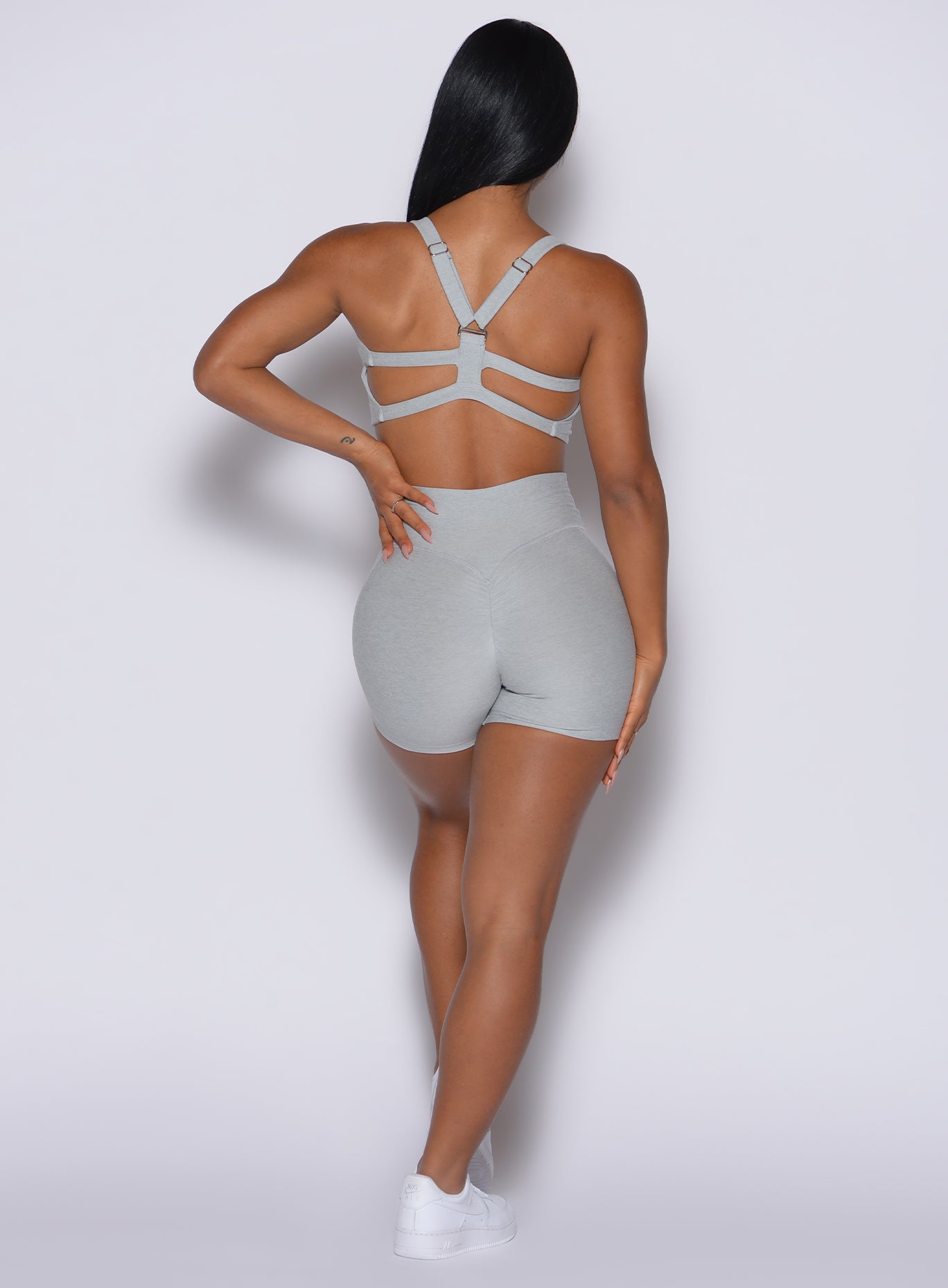 back profile view of a model wearing our Tiny Waist Shorts in light cloud color along with the matching bra