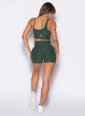 back profile of a model wearing the Tiny Waist Shorts and the matching Asymmetrical Slit Bra in Pine color