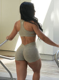 back profile view of a model in indoors wearing the V Back Shorts in toasted Sugar color paired with the matching Powerhouse bra in Toasted Sugar color