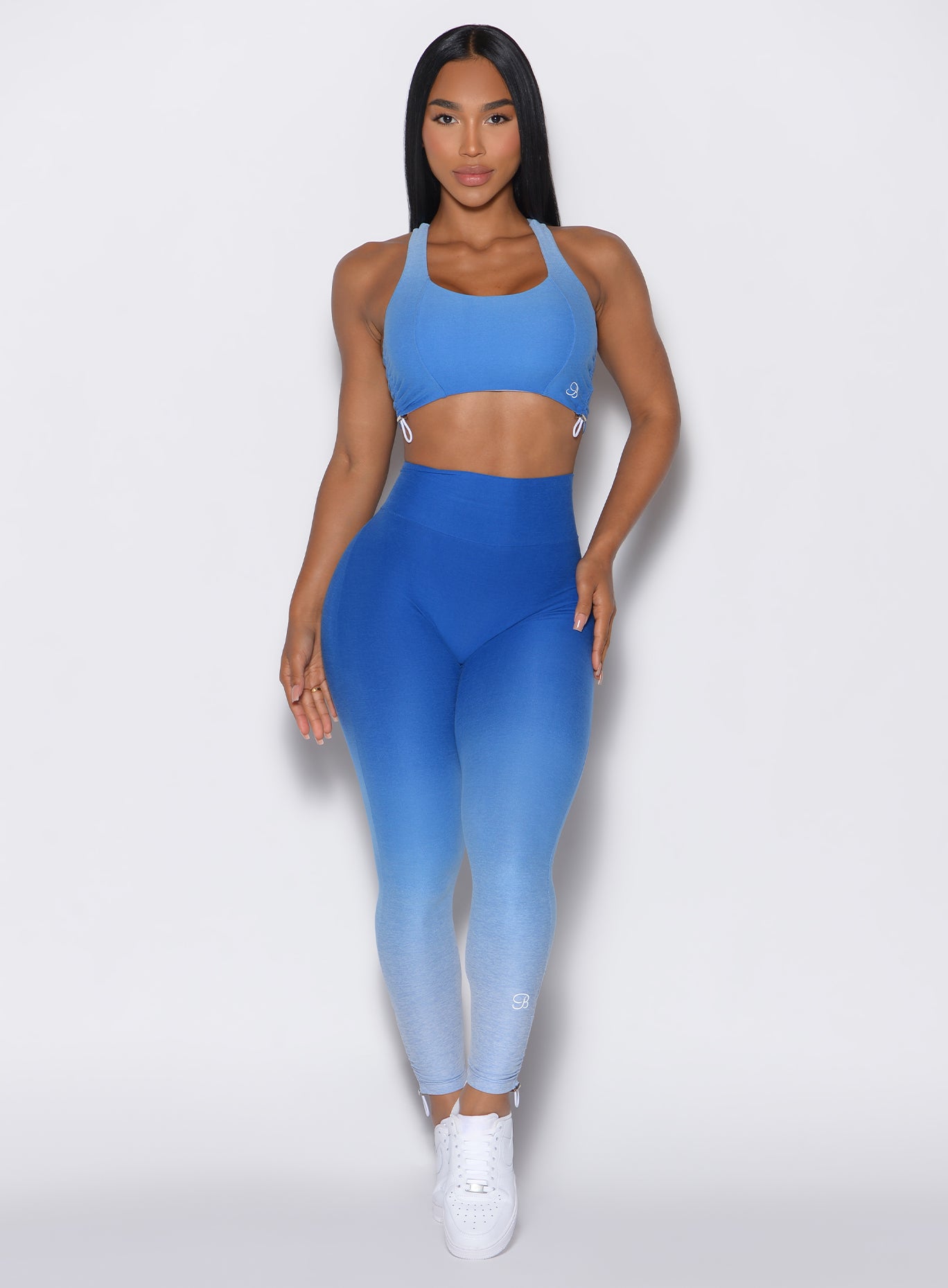 Front profile view of a model wearing our toggle leggings in Ombre Blue Crush color along with the matching sports bra 