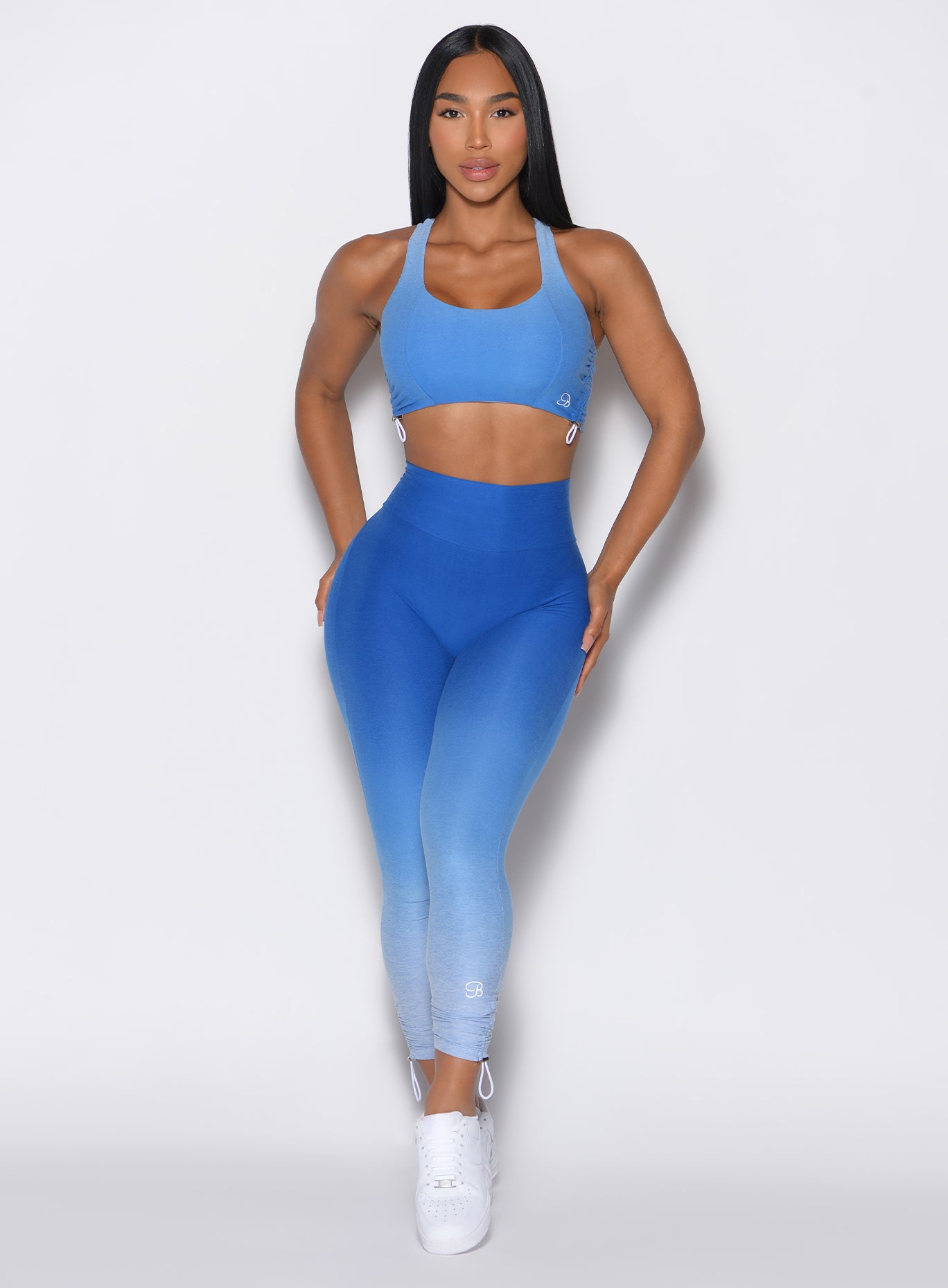 front profile view of a model facing forward wearing our toggle leggings in Ombre Blue Crush color along with the matching sports bra