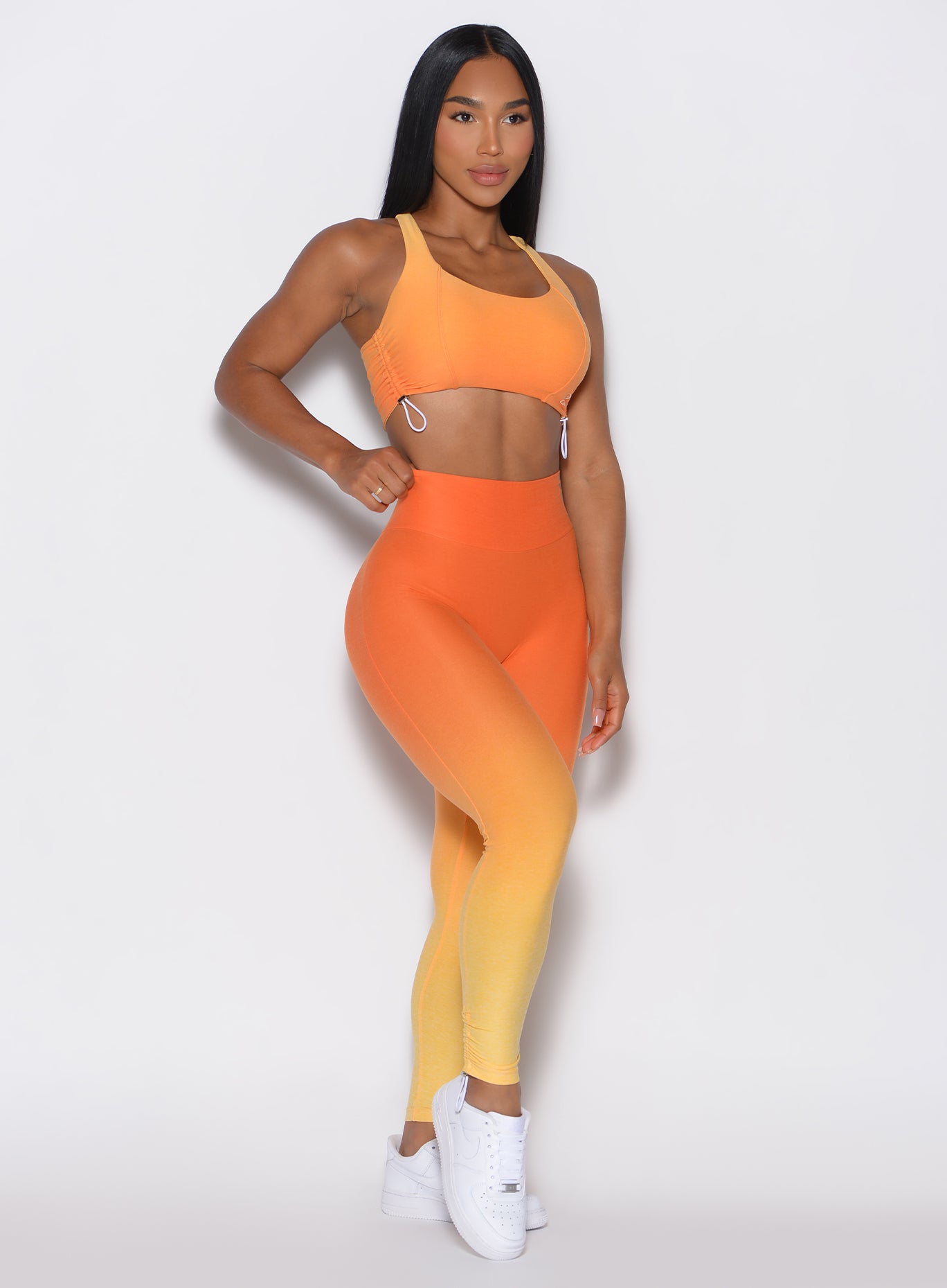 front profile picture of a model wearing our toggle leggings in Ombre Hawaiian Punch color along with the matching bra