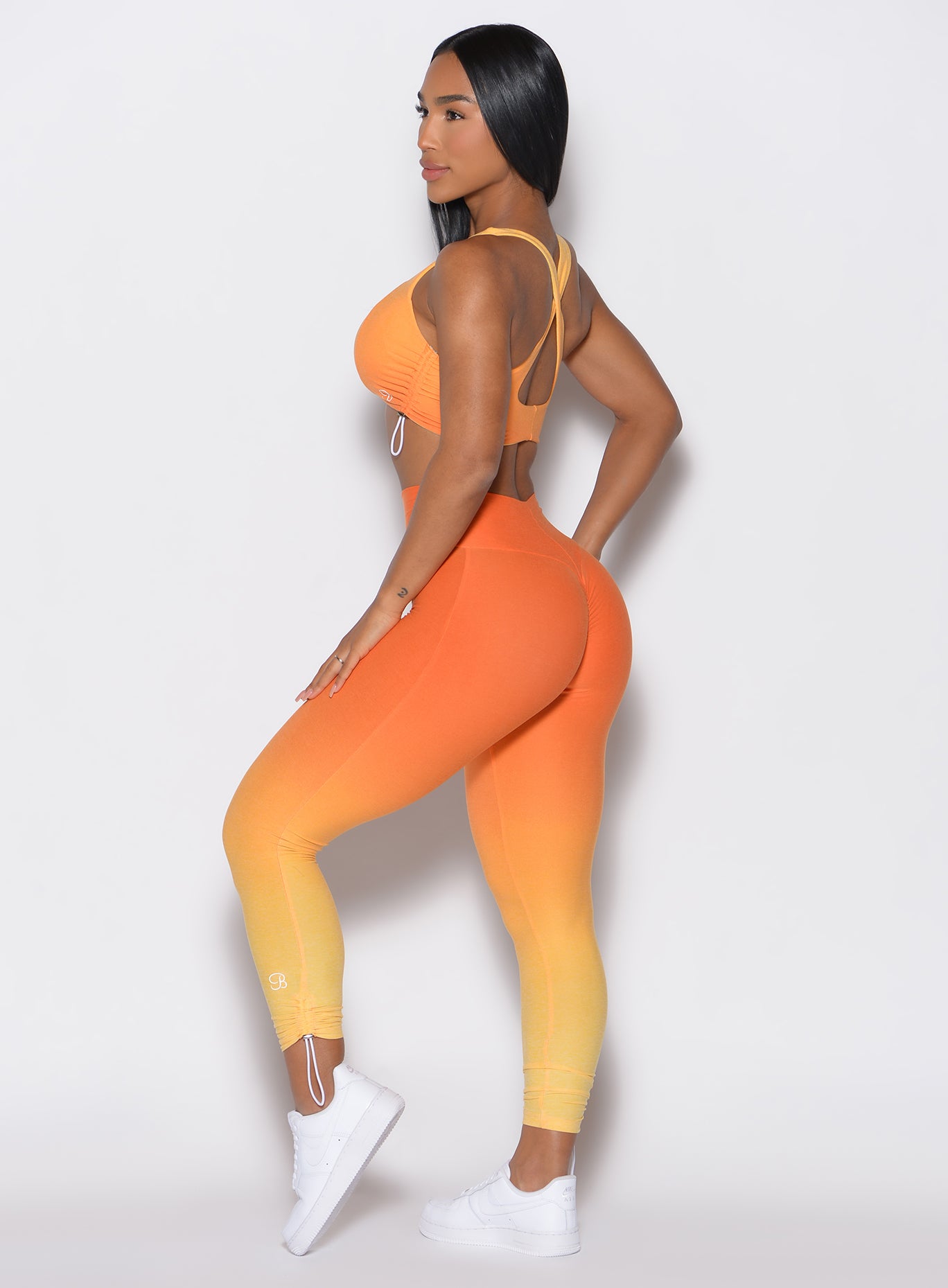 left side profile view of a model wearing our toggle leggings in Ombre Hawaiian Punch color along with the matching toggle sports bra