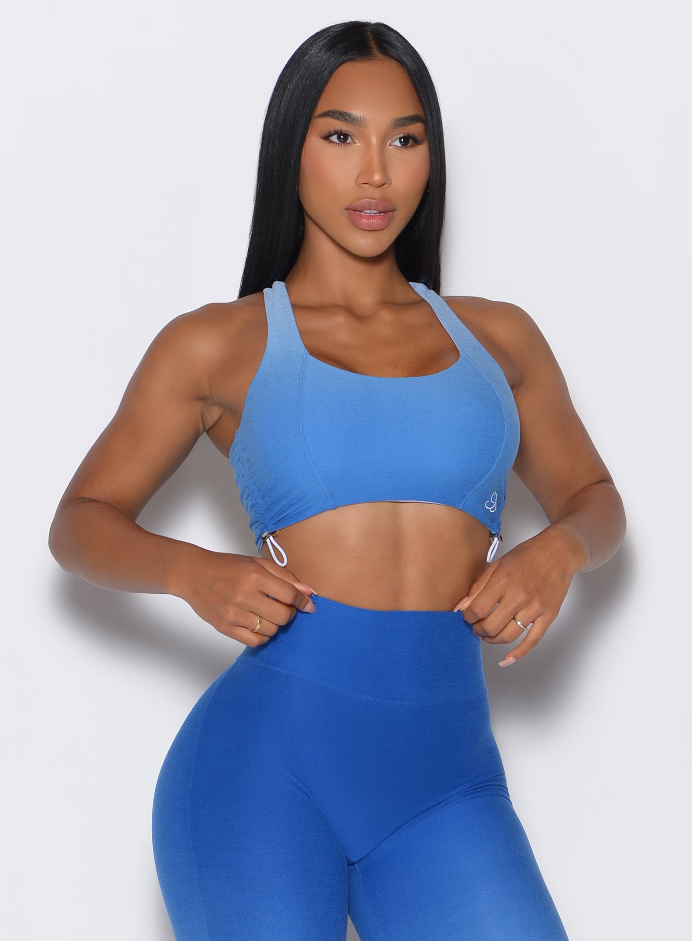 front profile view of a model wearing our toggle sports bra in Ombre Blue Crush color along with the matching toggle leggings