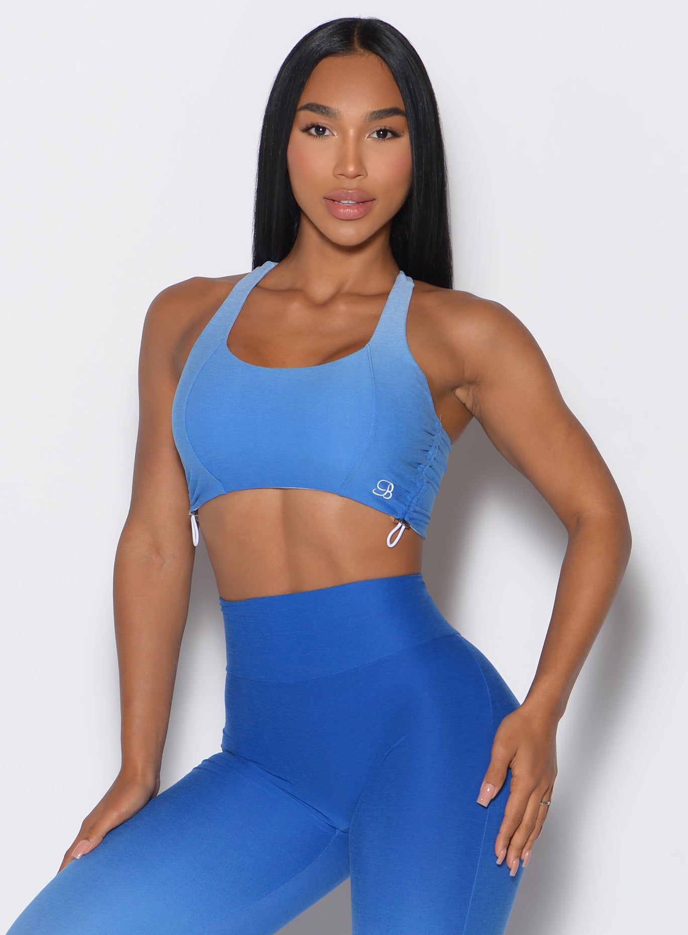 front profile view of a model wearing our toggle sports bra in Ombre Blue Crush color complemented with the matching toggle leggings