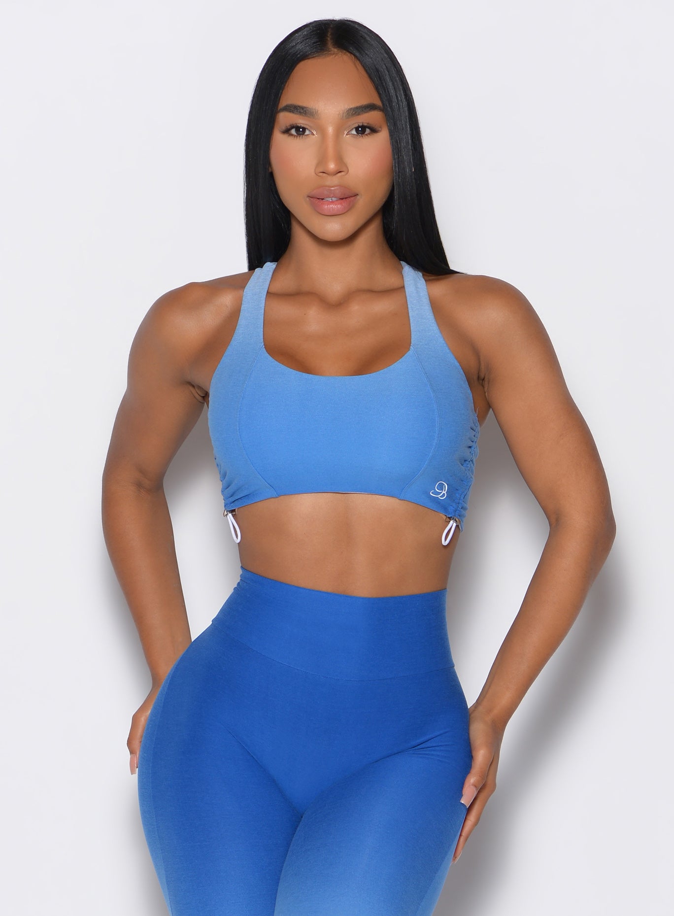front profile view of a model wearing our toggle sports bra in Ombre Blue Crush color along with the matching leggings 