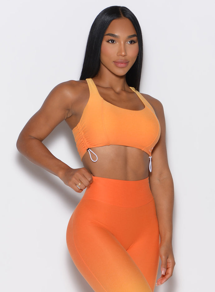 front profile picture of a model wearing our toggle sports bra in Ombre Hawaiian Punch color along with the matching leggings