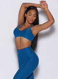 Left side profile picture of a model with her hands over her head wearing our topnotch bra in azure color and a matching leggings