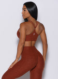 Back profile picture of a model facing to her left wearing our topnotch bra in cinnamon color and a matching leggings