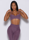 Front profile view of a model wearing our top notch bra in regal purple color along with the matching leggings 