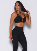 Right side profile view of a model angled slightly to her right wearing our black twist sports bra and a matching leggings