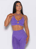 Front profile view of a model wearing our twist sports bra in royal purple color along with a matching leggings