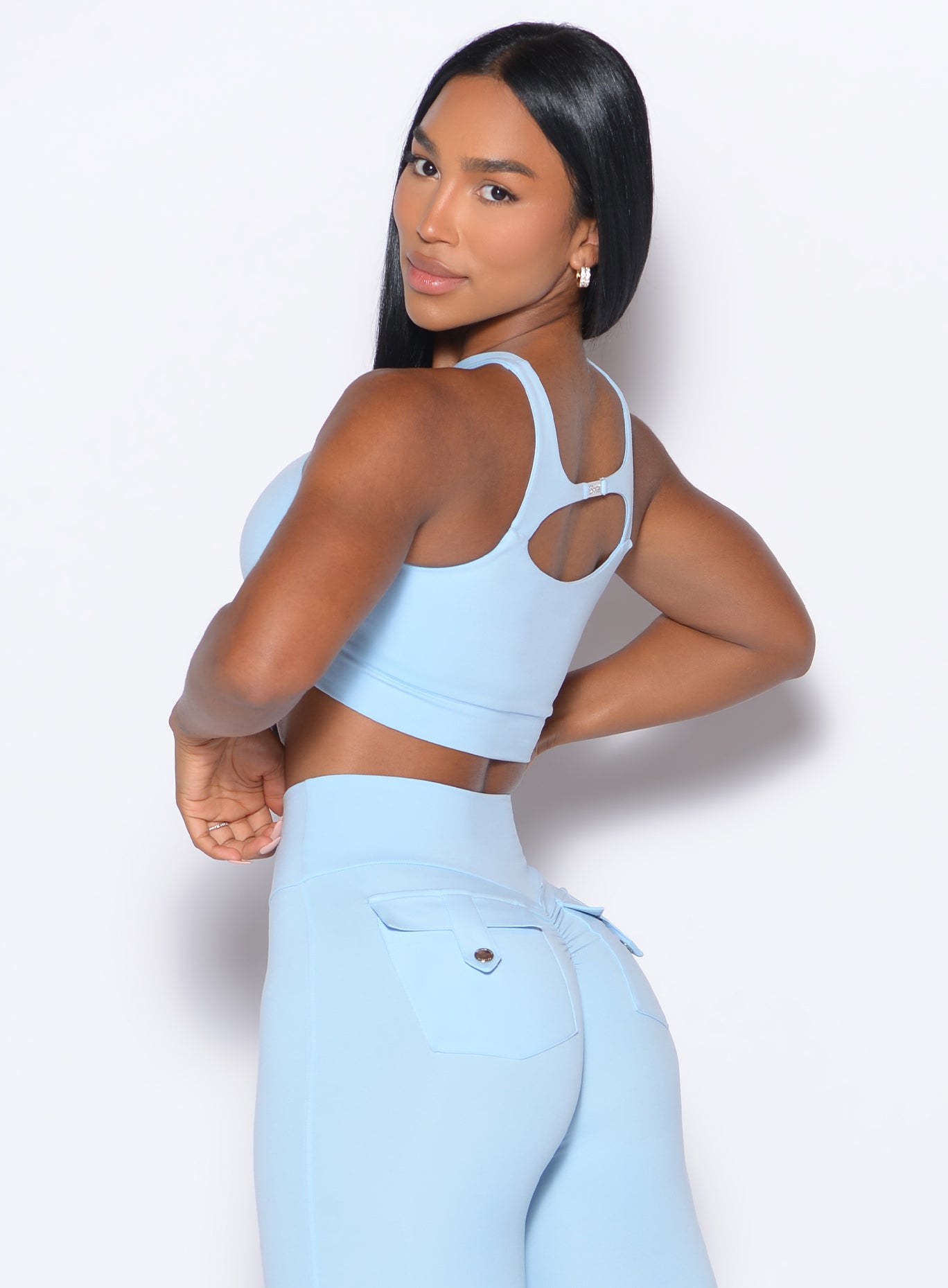 back profile view of a model looking to her back wearing our Two Way Bra in Glacial Blue color and a matching leggings 
