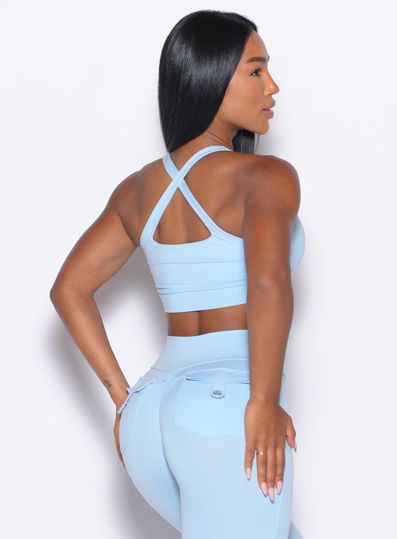 back profile of a model wearing the Two Way Bra in Glacial Blue color and a matching leggings 
