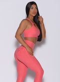 Right side profile view of a model in our two way bra in papaya color and a matching leggings