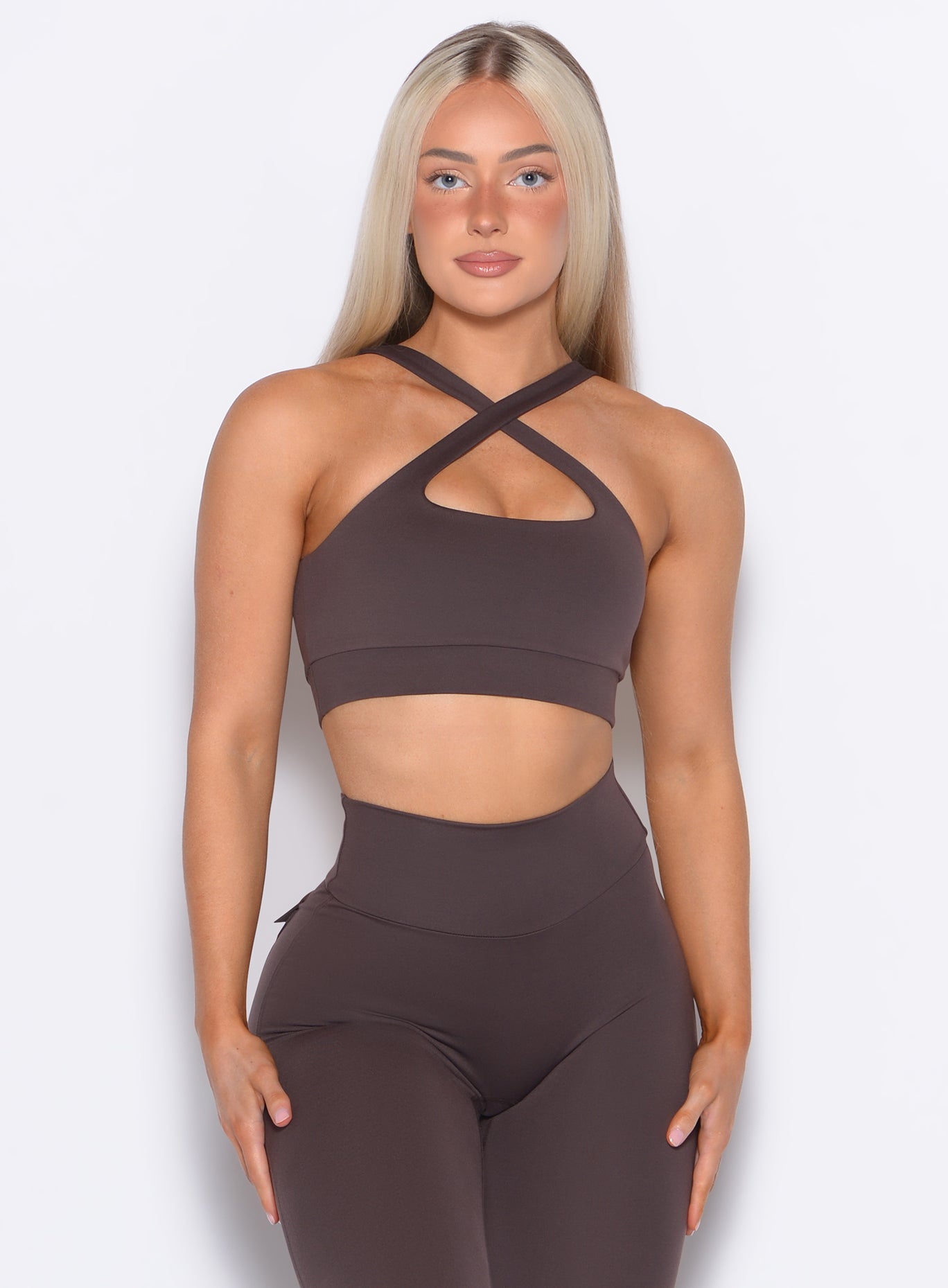 front profile view of a model posing in our Two Way Bra in Seal Brown color and a matching leggings 
