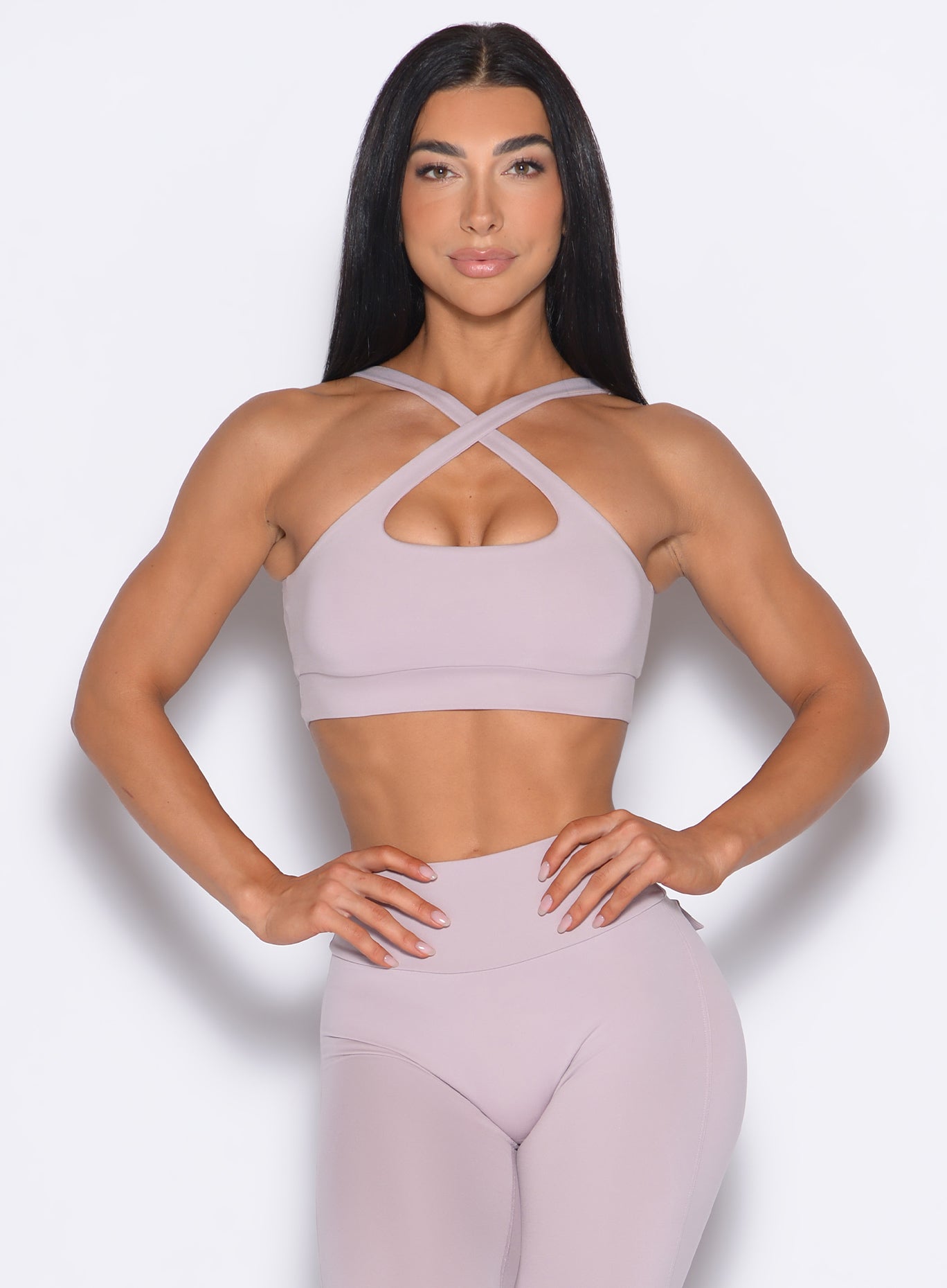 front profile view of a model wearing our Two Way Bra in Violet Ice color and a matching leggings 
