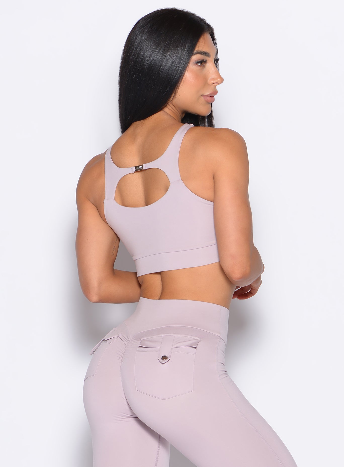 back profile view of a model facing to her right wearing our Two Way Bra in Violet Ice color and a matching leggings