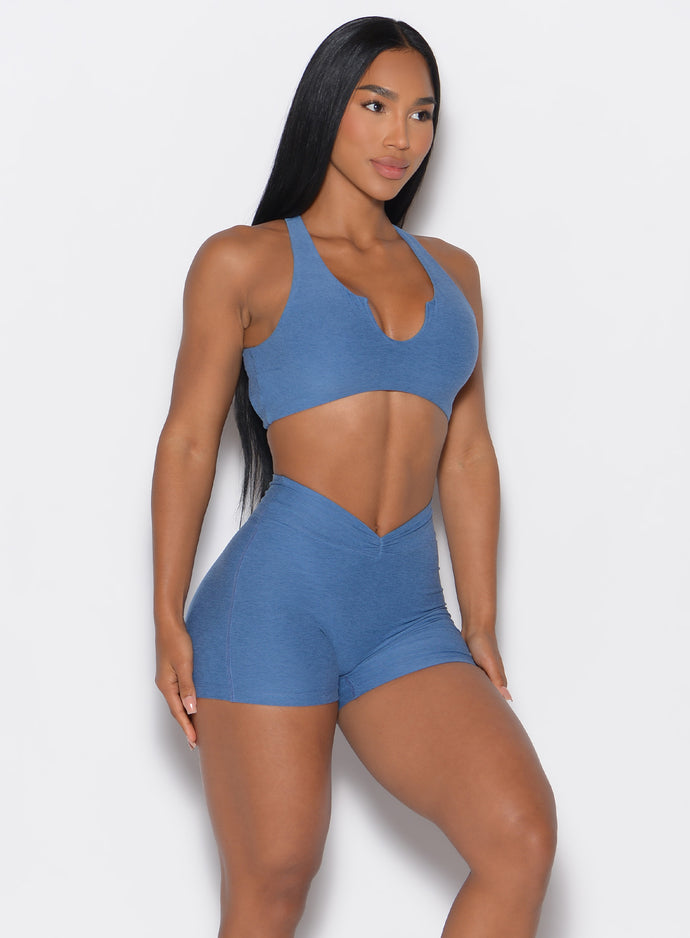 front profile view of a model angled slightly to her left wearing our V Active Shorts and the matching bra in Chambray color