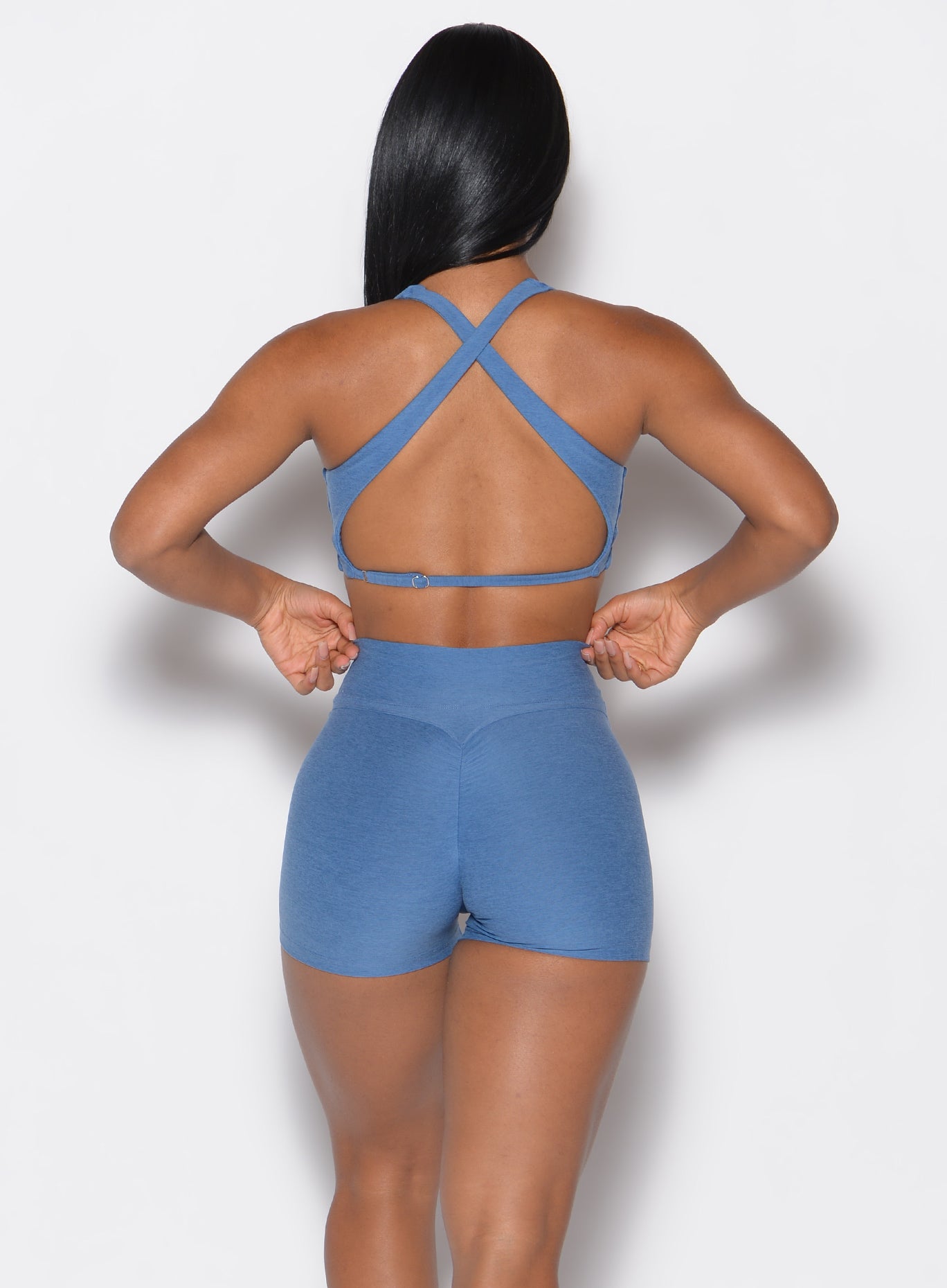 back profile view of a model wearing our V Active Shorts and the matching bra in Chambray color