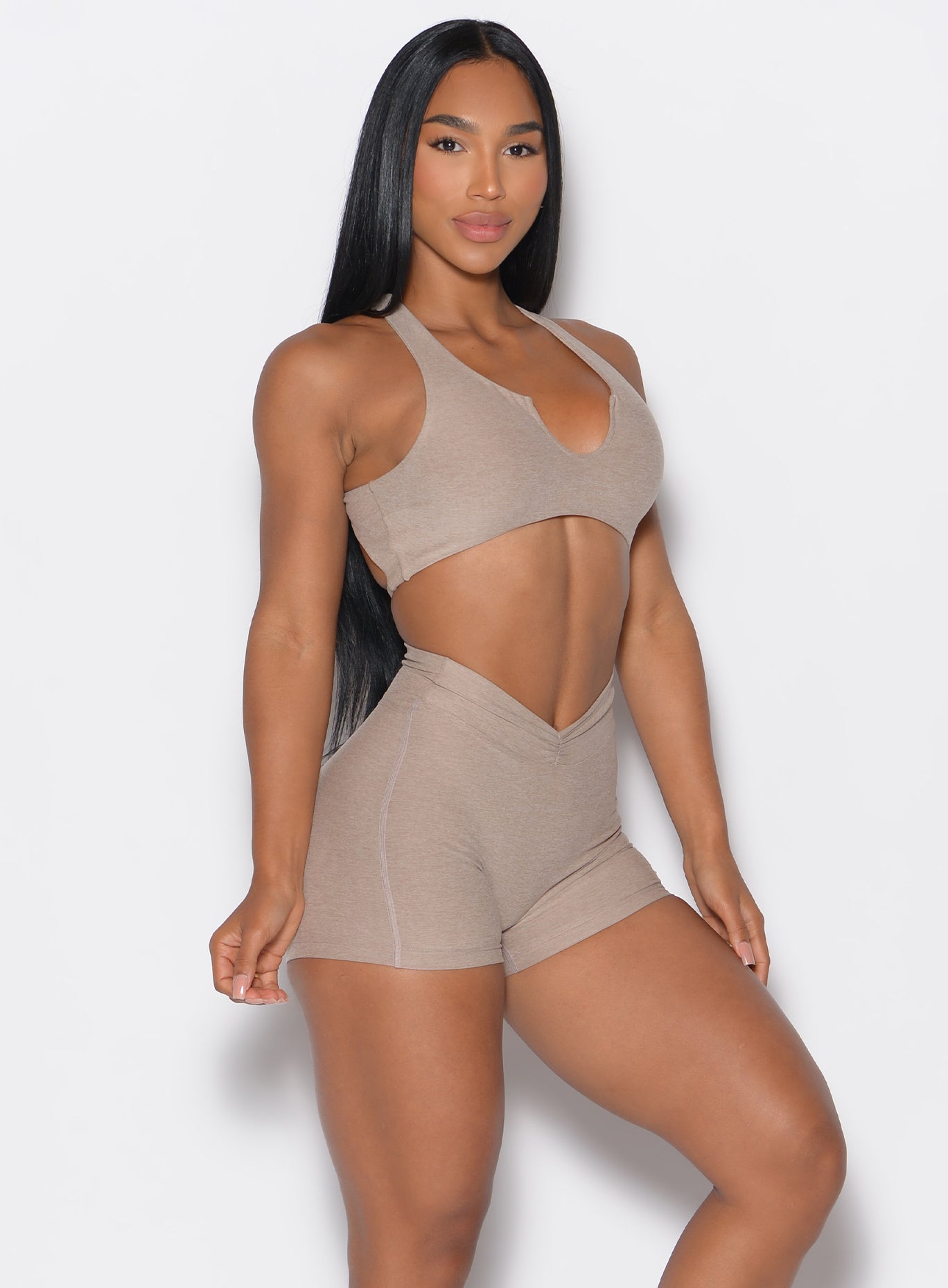 Right side view of a model facing to her right wearing our V Active Shorts and the matching bra in Desert Taupe color