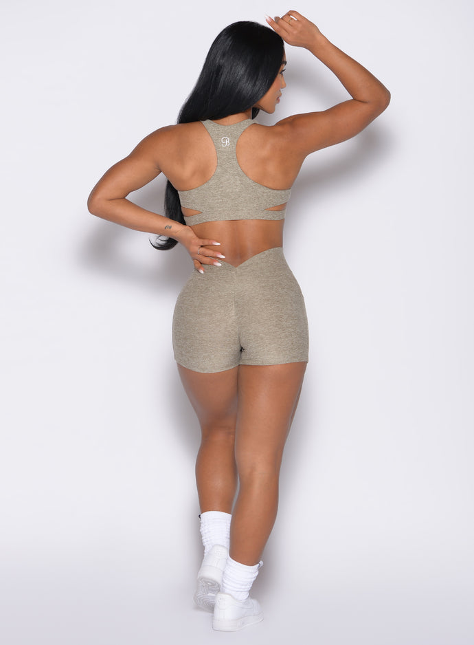 back profile view of a model with one hand on her waist wearing the V Back Shorts in toasted Sugar color