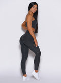 right side profile view of a model facing to her right wearing our V Active Leggings in charcoal color along with the matching top