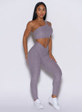 right side profile view of a model angled right wearing our V Active Leggings in lilac gray color along with the matching top