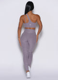 back profile view of a model wearing our V Active Leggings in lilac gray color along with the matching top