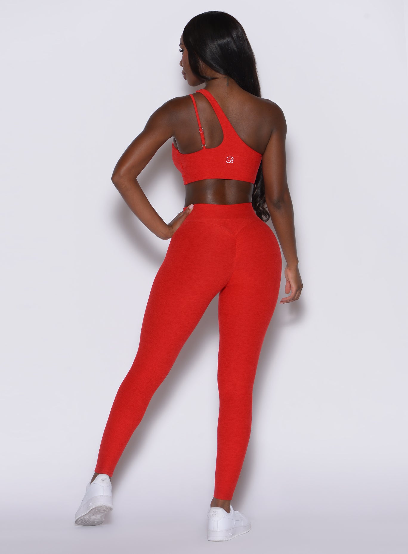 back profile view of a model wearing our V Active Leggings in scarlet red along with the matching top