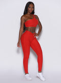 right side profile view of a model angled right wearing our V Active Leggings in scarlet red along with the matching top