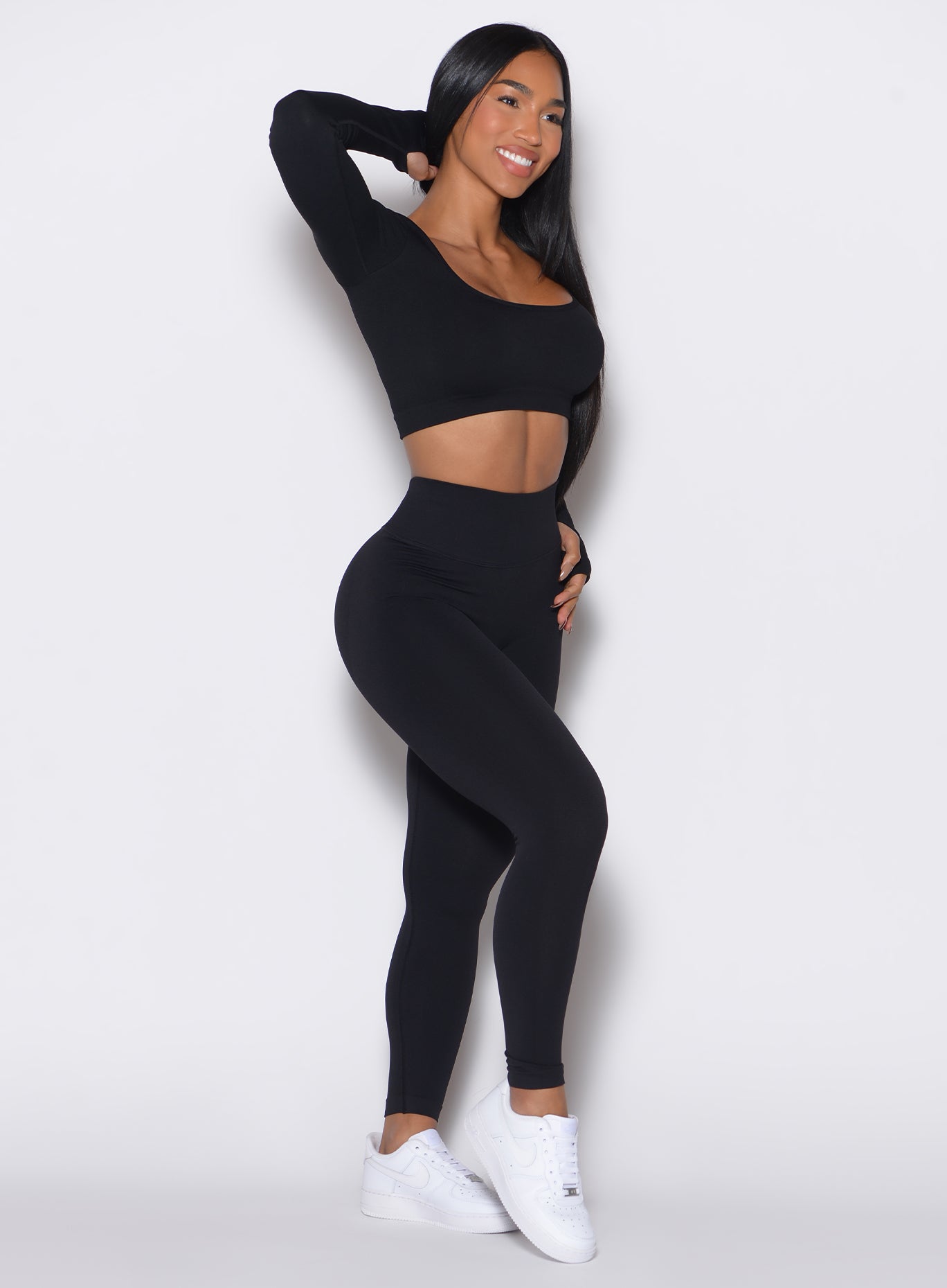 right side profile view of a model wearing our black V Seamless Leggings along with a matching pullover