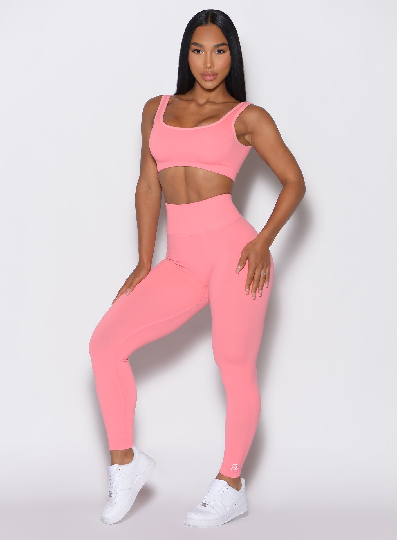 Front profile view of a model wearing our v seamless leggings in flamingo color along with a matching sports bra 